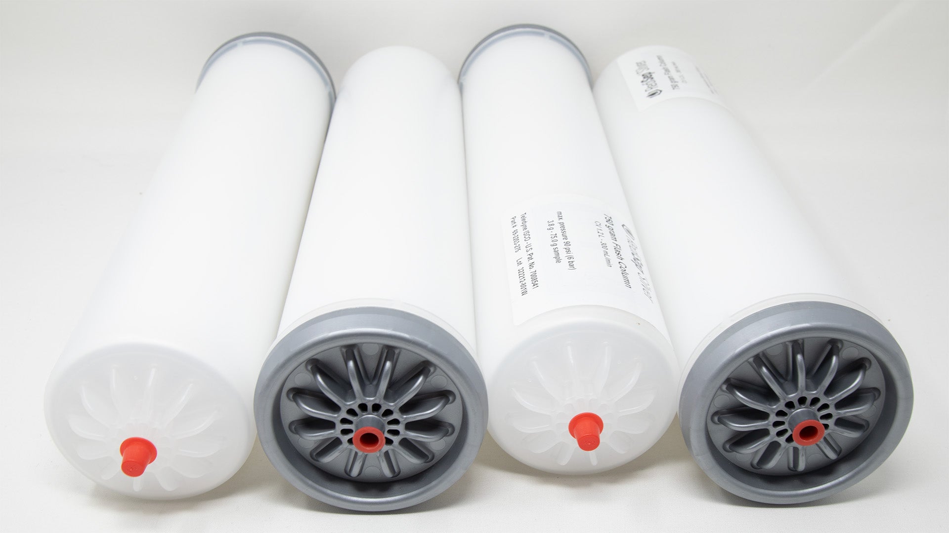 A group of plastic tubes with red and silver caps, positioned side by side, emphasizing their contrasting colors and forms.