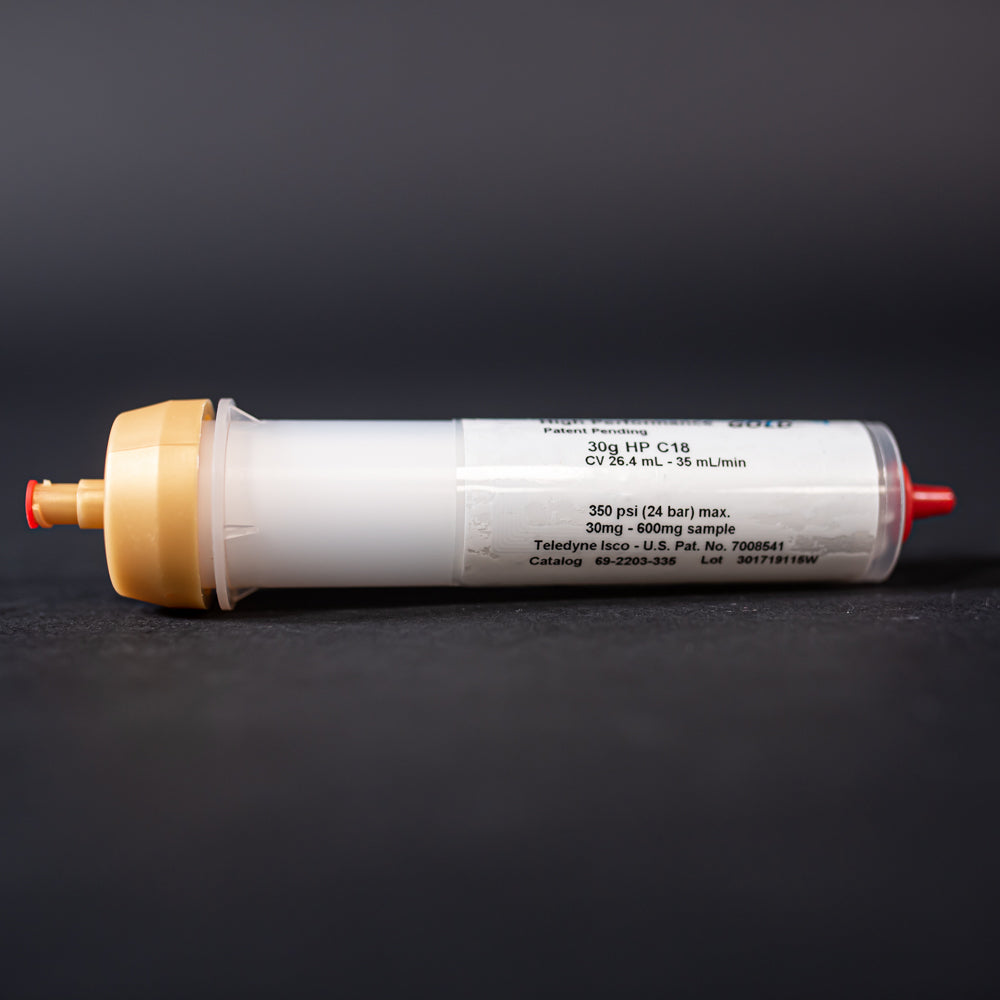 A small white tube with gold and red caps displayed on a black background, creating a striking visual contrast between the two elements.