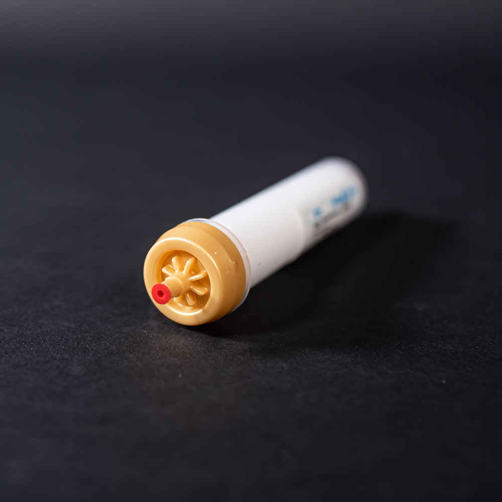 A small white tube with gold and red caps displayed on a black background, creating a striking visual contrast between the two elements.