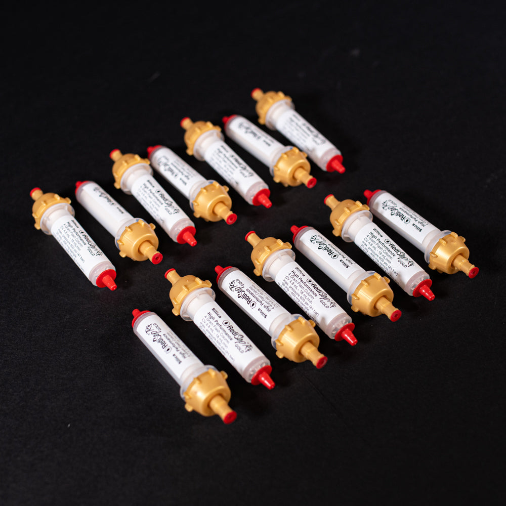 A group of small white tubes with gold and red caps displayed on a black background, creating a striking visual contrast between the two elements.
