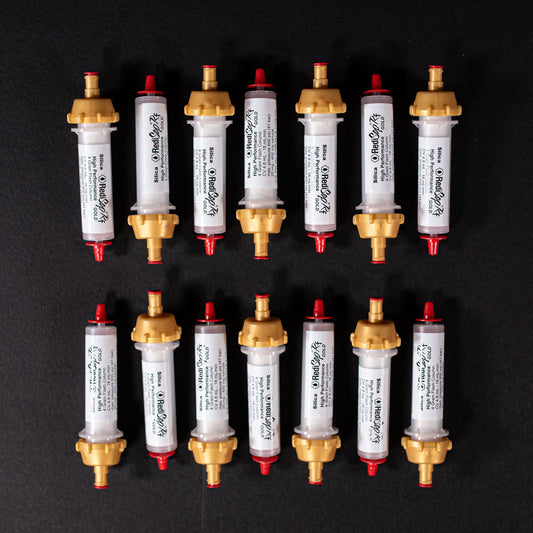 A group of small white tubes with gold and red caps displayed on a black background, creating a striking visual contrast between the two elements.