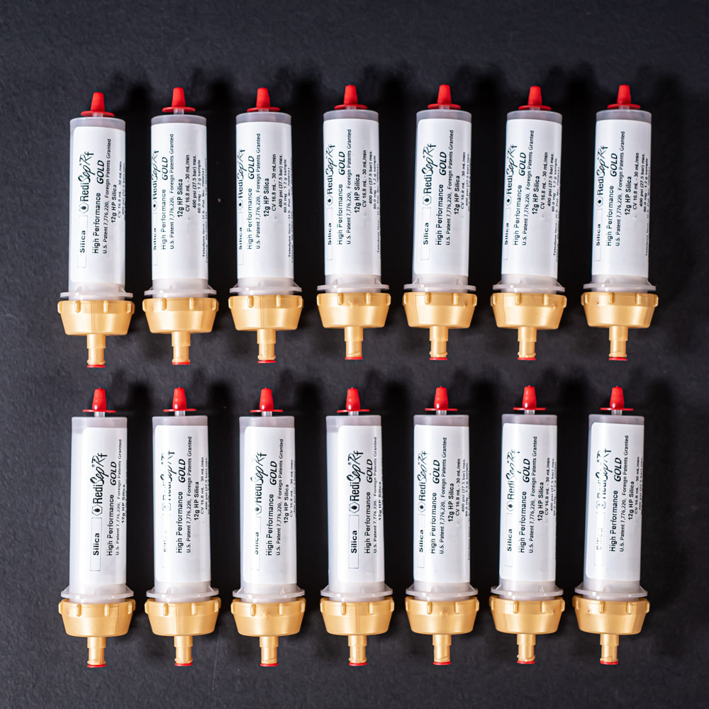 A group of small white tubes with gold and red caps displayed on a black background, creating a striking visual contrast between the two elements.