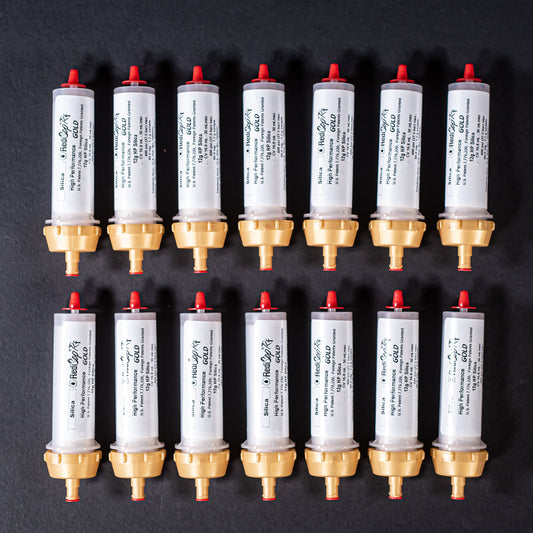 A group of small white tubes with gold and red caps displayed on a black background, creating a striking visual contrast between the two elements.