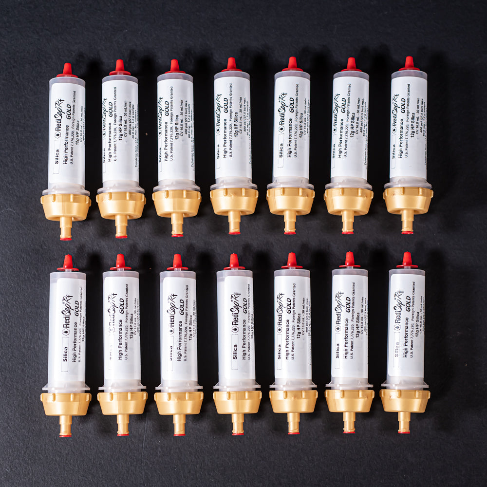 A group of small white tubes with gold and red caps displayed on a black background, creating a striking visual contrast between the two elements.