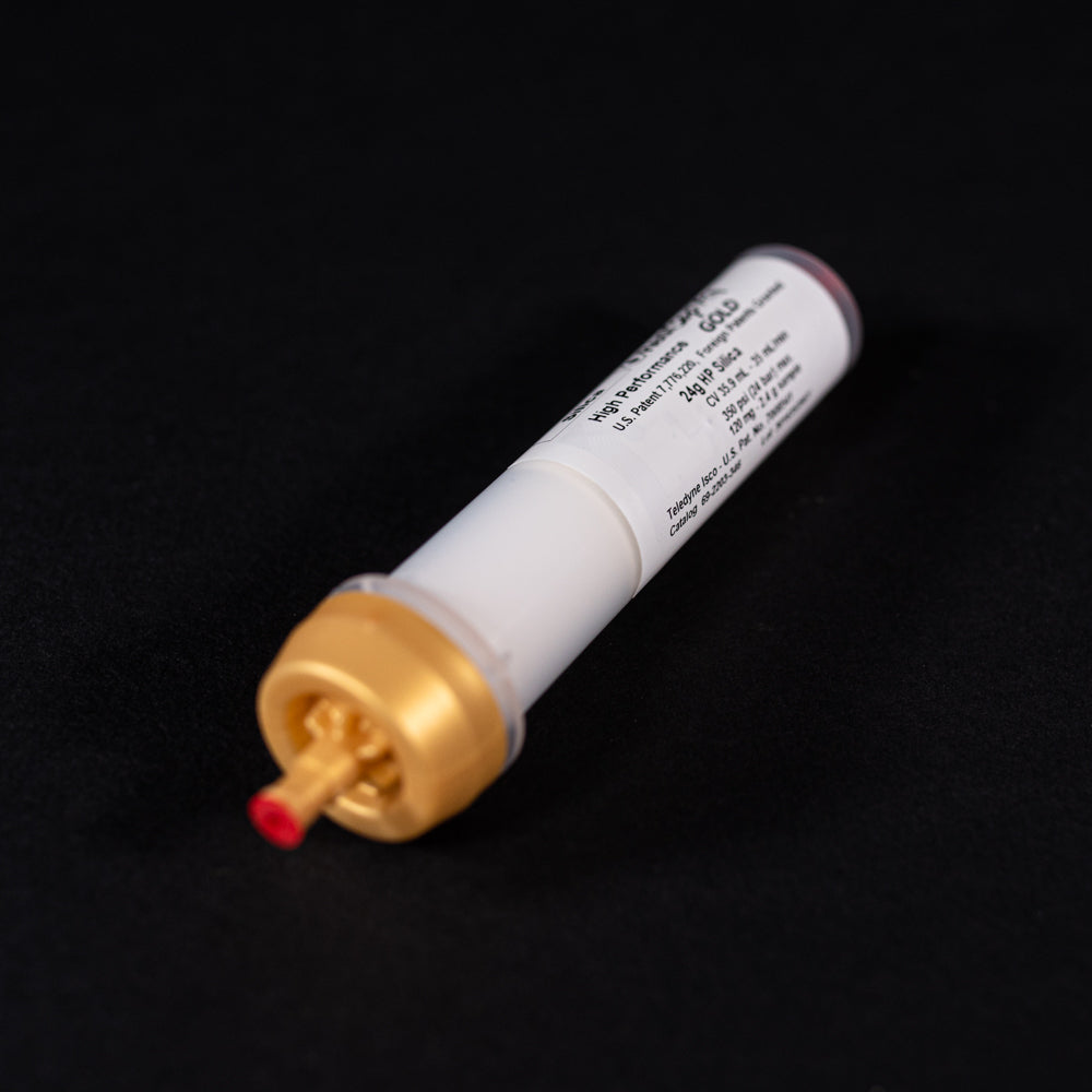 A small white tube with gold and red caps displayed on a black background, creating a striking visual contrast between the two elements.