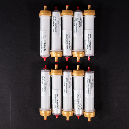 A group of small white tubes with gold and red caps displayed on a black background, creating a striking visual contrast between the two elements.