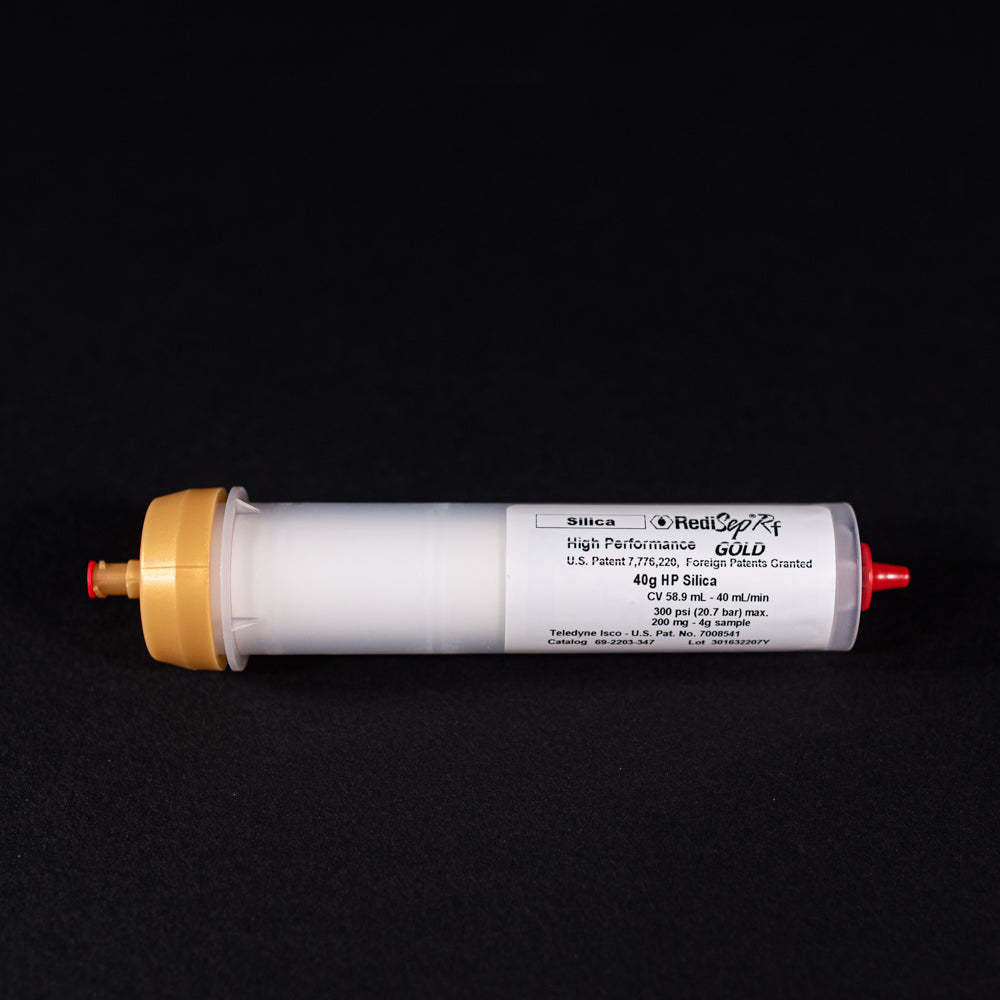 A small white tube with gold and red caps displayed on a black background, creating a striking visual contrast between the two elements.