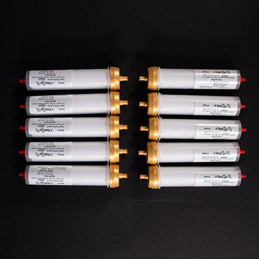 A group of small white tubes with gold and red caps displayed on a black background, creating a striking visual contrast between the two elements.
