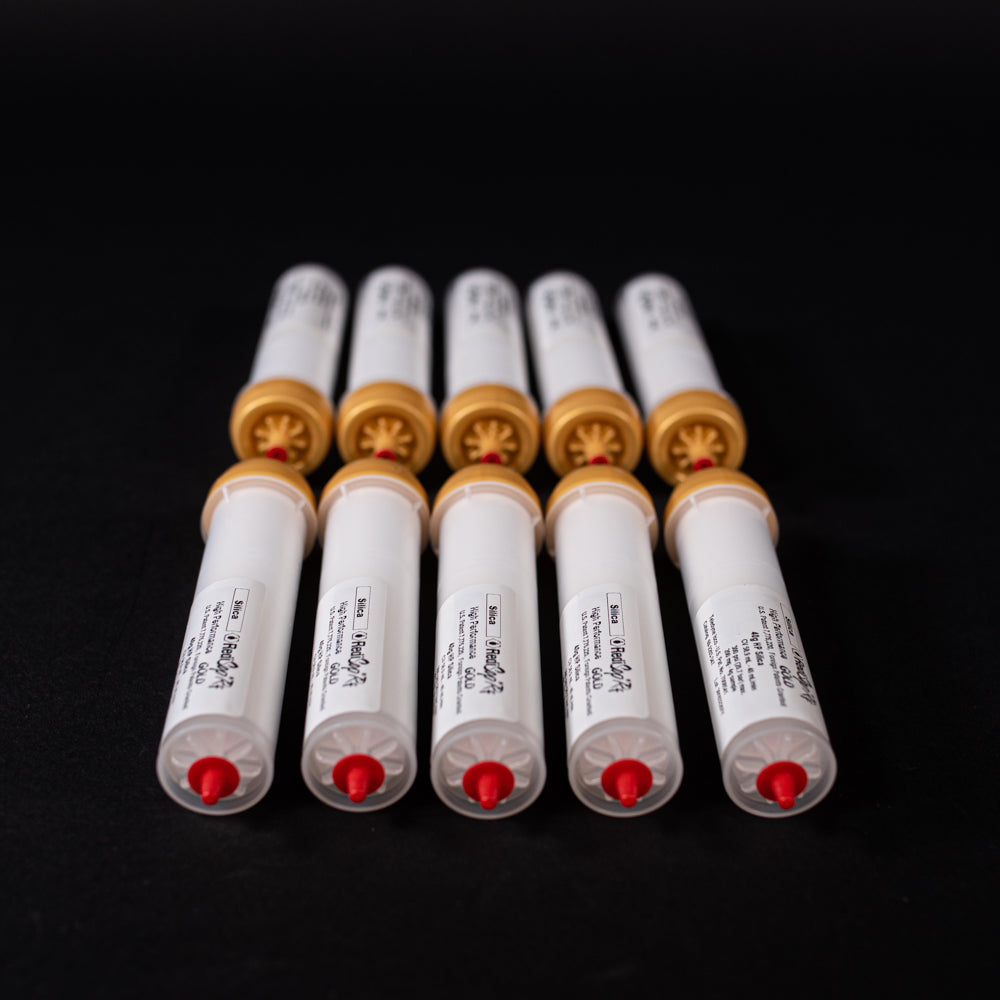 A group of small white tubes with gold and red caps displayed on a black background, creating a striking visual contrast between the two elements.