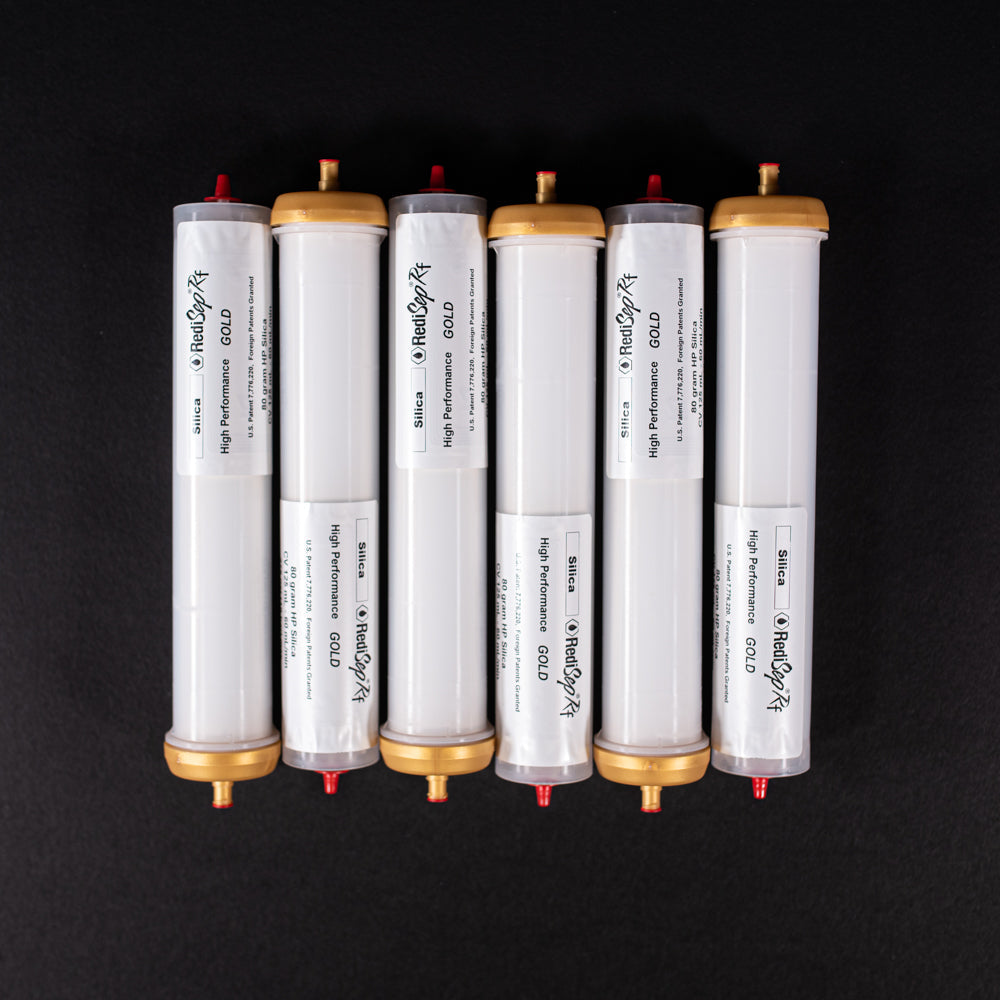 A group of small white tubes with gold and red caps displayed on a black background, creating a striking visual contrast between the two elements.