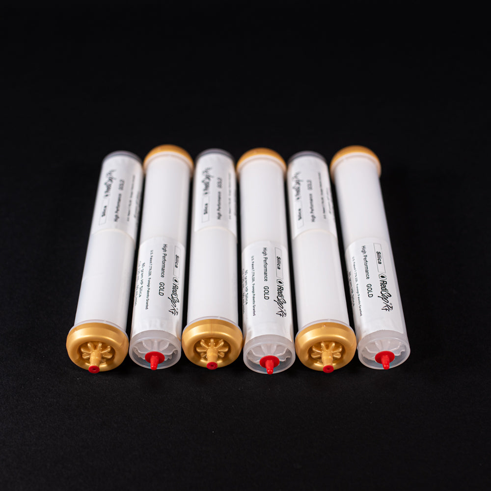 A group of small white tubes with gold and red caps displayed on a black background, creating a striking visual contrast between the two elements.