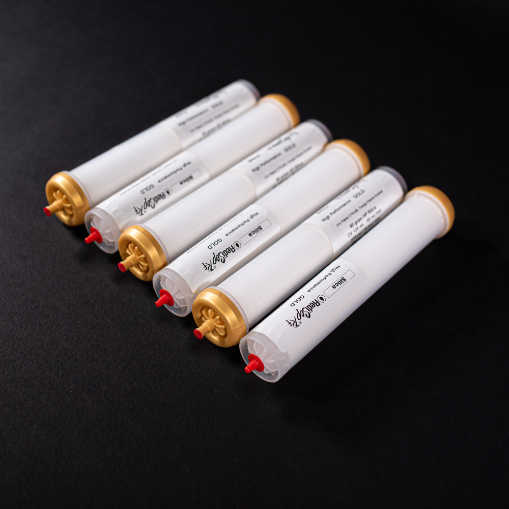 A group of small white tubes with gold and red caps displayed on a black background, creating a striking visual contrast between the two elements.