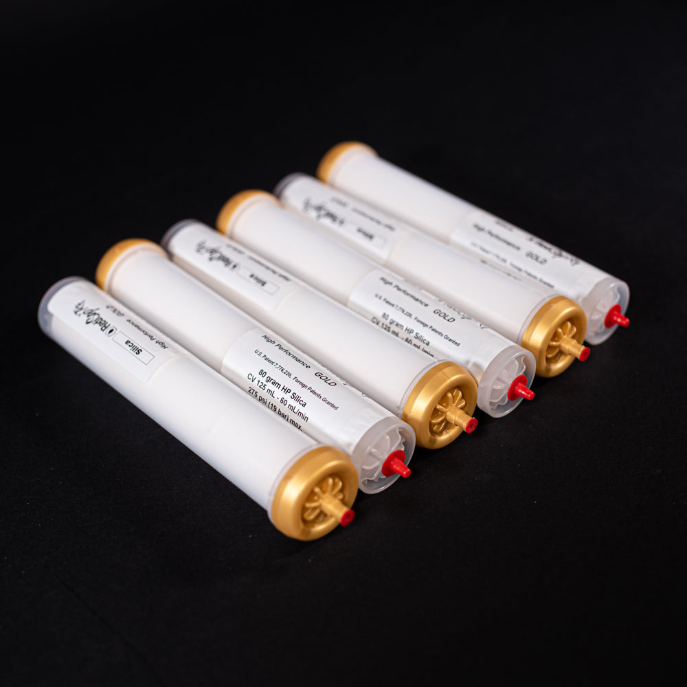 A group of small white tubes with gold and red caps displayed on a black background, creating a striking visual contrast between the two elements.