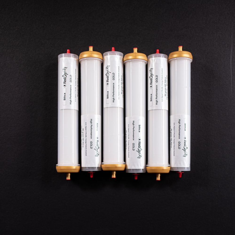 A group of small white tubes with gold and red caps displayed on a black background, creating a striking visual contrast between the two elements.