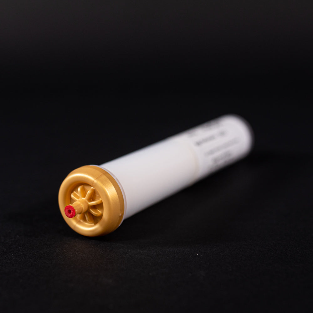 A small white tube with gold and red caps displayed on a black background, creating a striking visual contrast between the two elements.