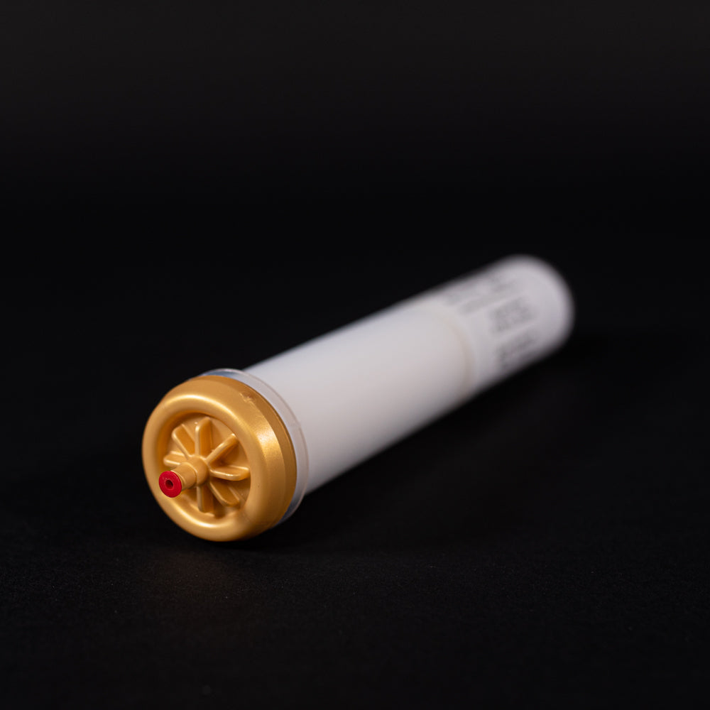 A small white tube with gold and red caps displayed on a black background, creating a striking visual contrast between the two elements.