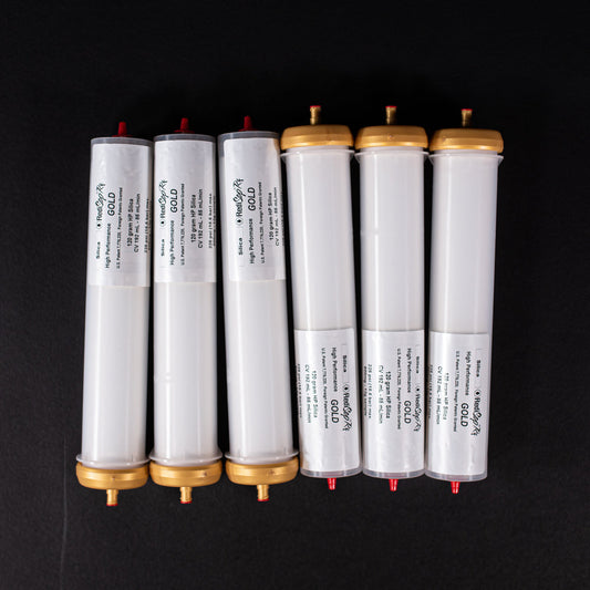 A group of small white tubes with gold and red caps displayed on a black background, creating a striking visual contrast between the two elements.