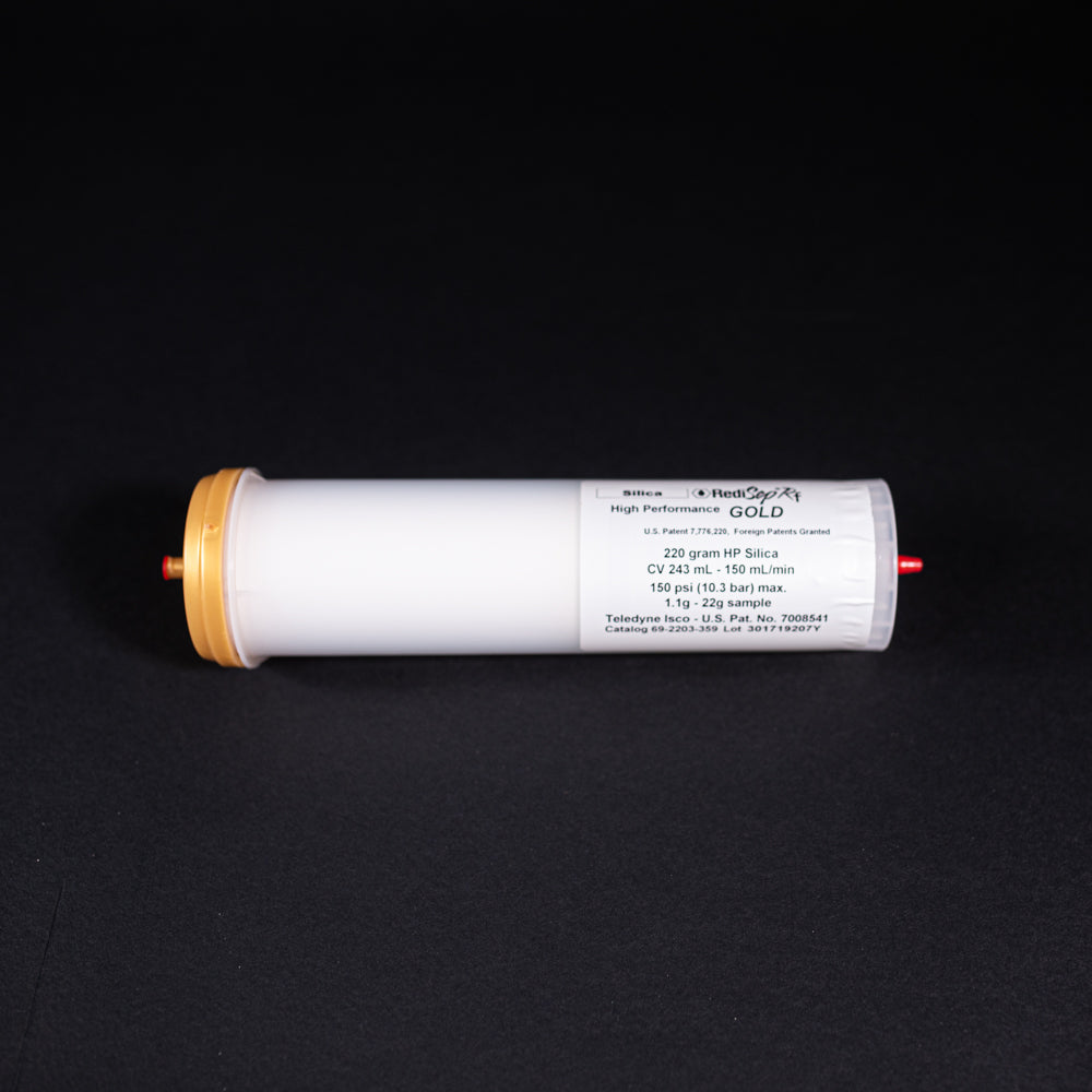 A small white tube with gold and red caps displayed on a black background, creating a striking visual contrast between the two elements.