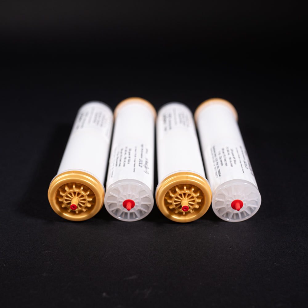 A group of small white tubes with gold and red caps displayed on a black background, creating a striking visual contrast between the two elements.