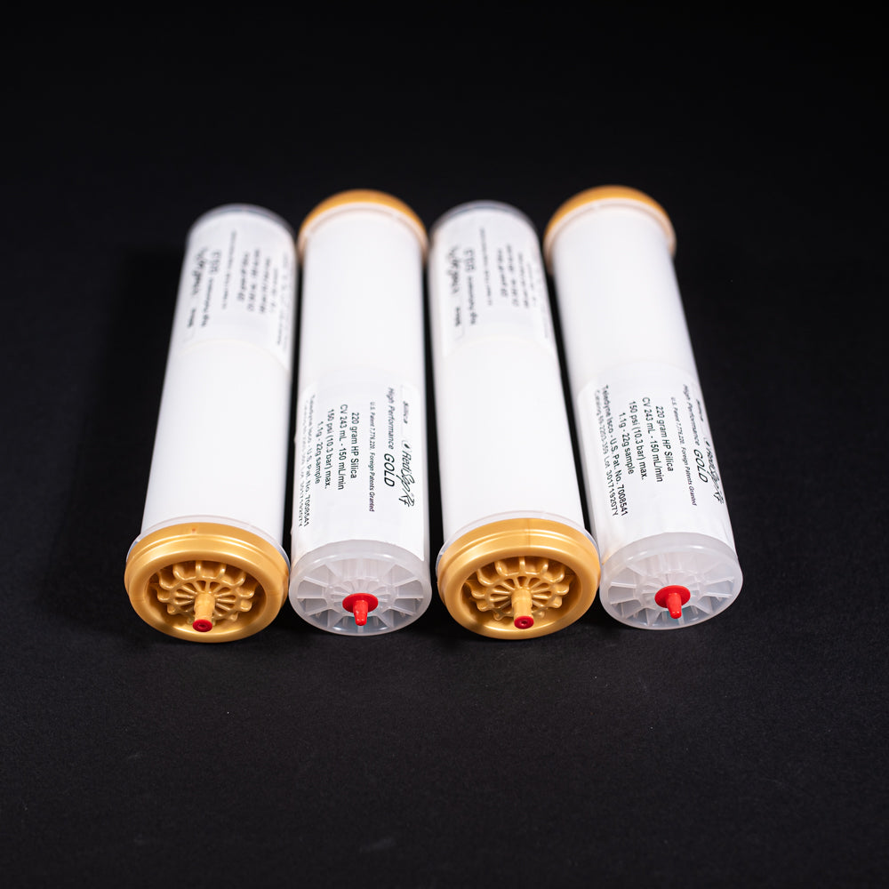 A group of small white tubes with gold and red caps displayed on a black background, creating a striking visual contrast between the two elements.