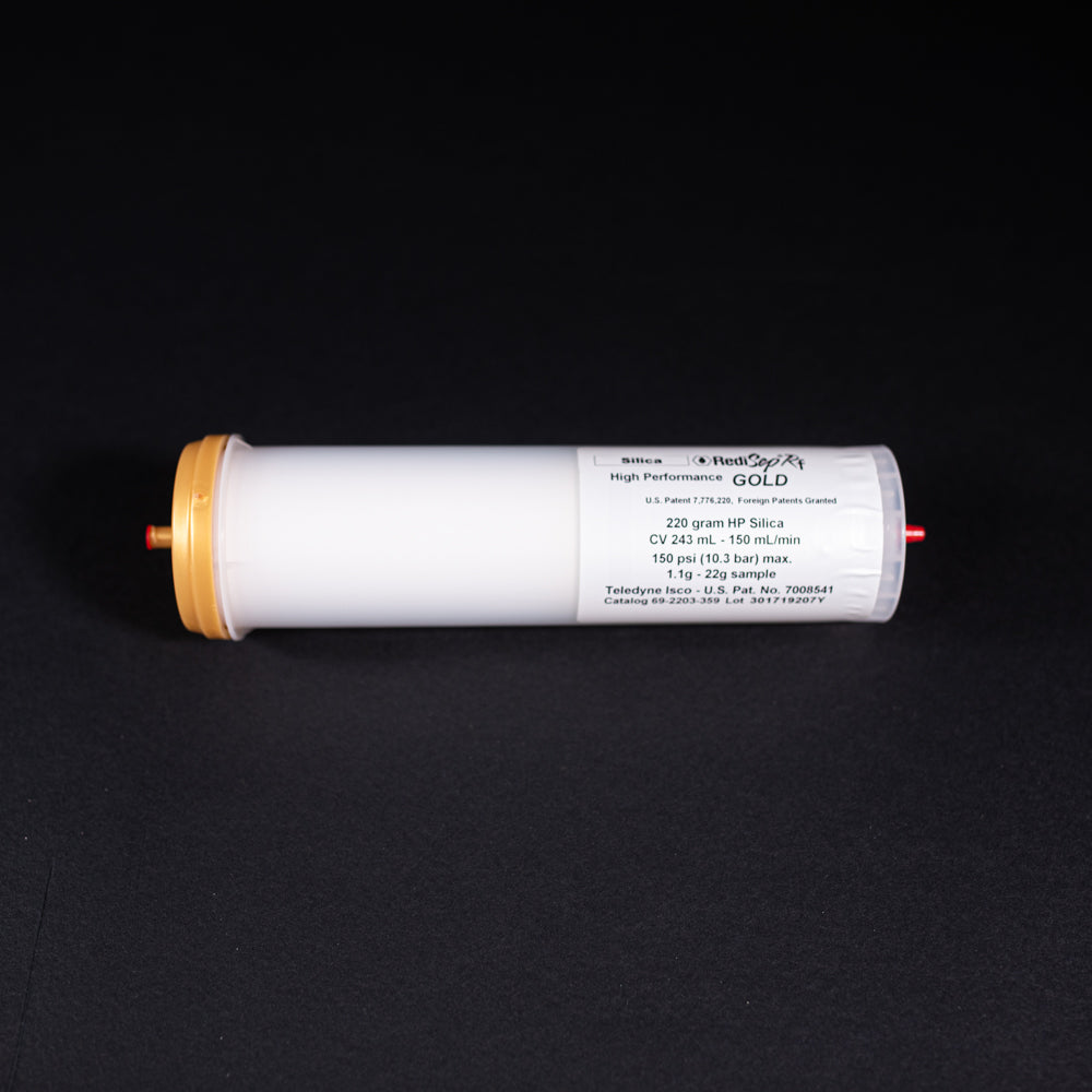 A small white tube with gold and red caps displayed on a black background, creating a striking visual contrast between the two elements.