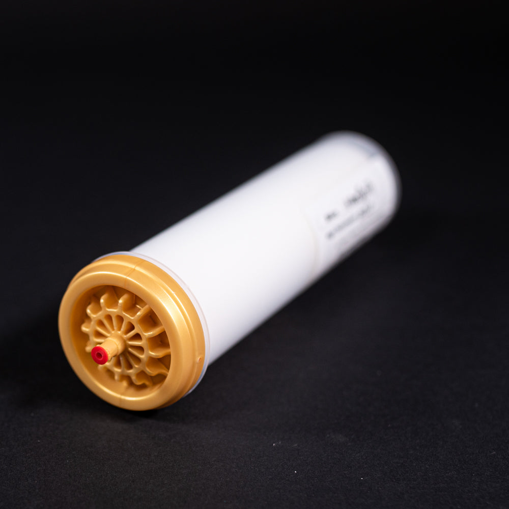 A small white tube with gold and red caps displayed on a black background, creating a striking visual contrast between the two elements.