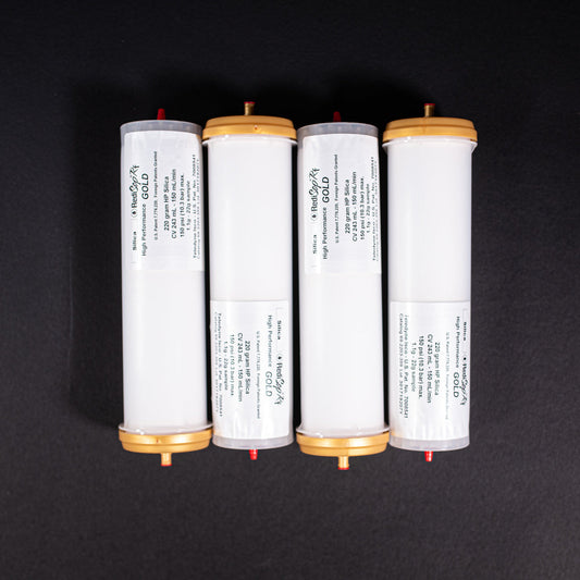 A group of small white tubes with gold and red caps displayed on a black background, creating a striking visual contrast between the two elements.