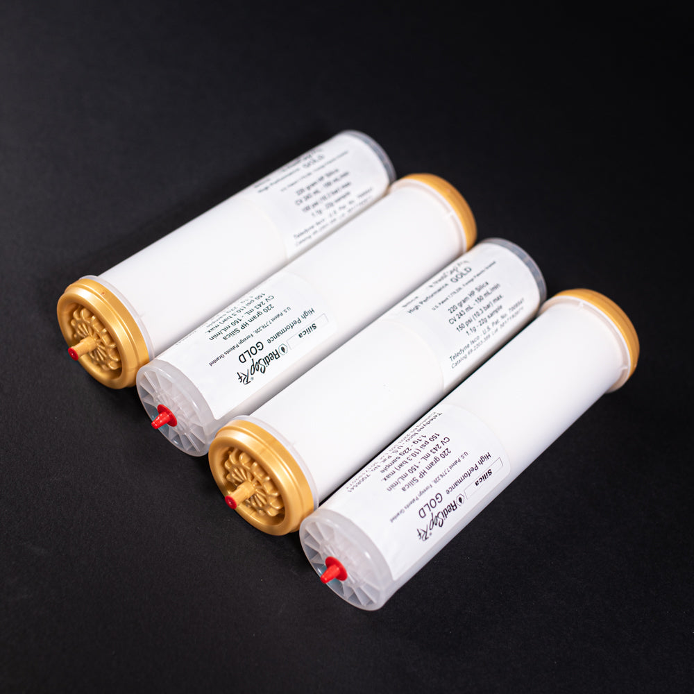 A group of small white tubes with gold and red caps displayed on a black background, creating a striking visual contrast between the two elements.