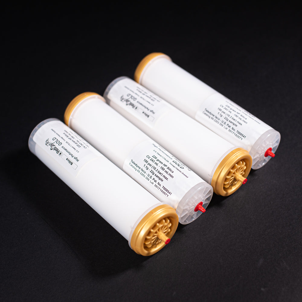A group of small white tubes with gold and red caps displayed on a black background, creating a striking visual contrast between the two elements.