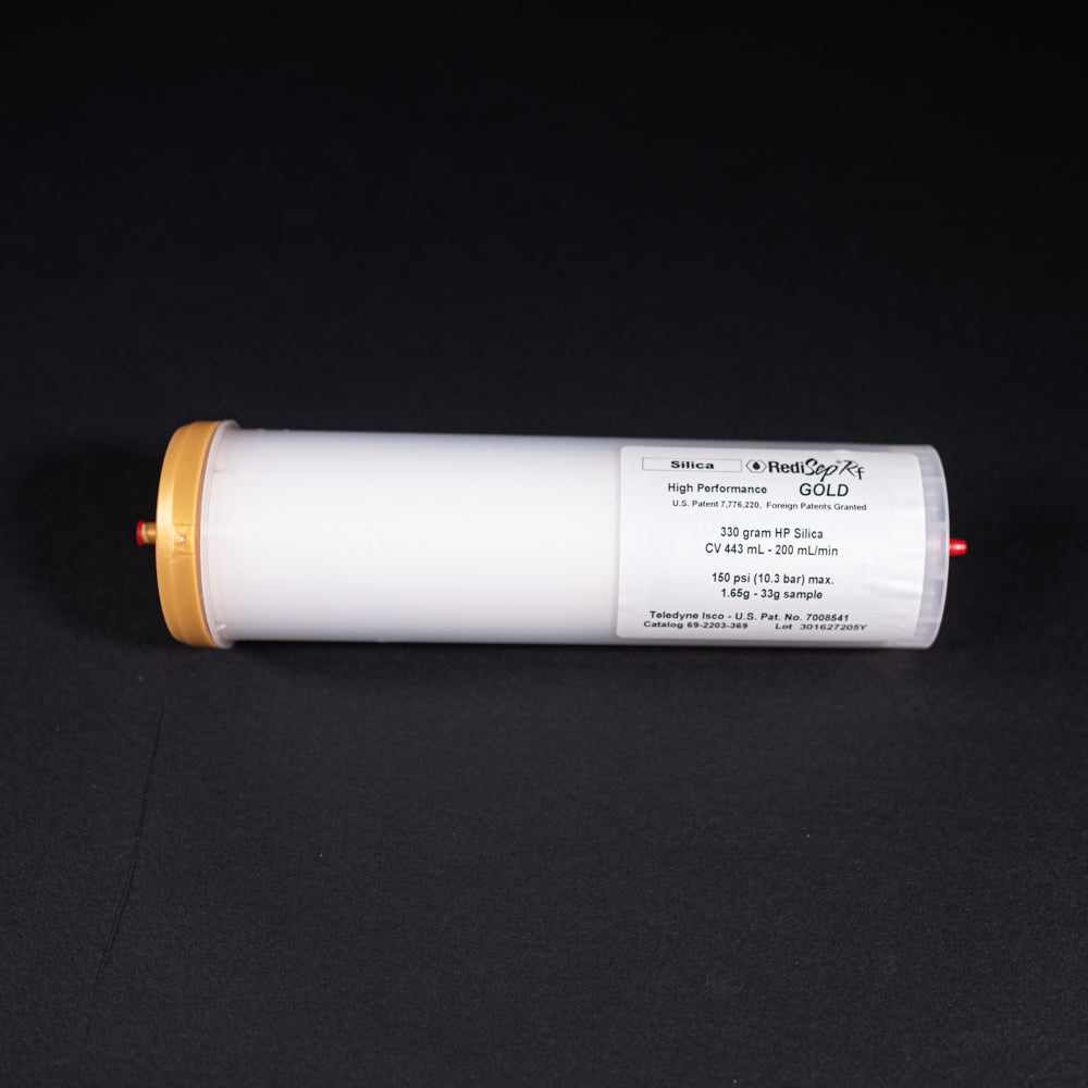 A small white tube with gold and red caps displayed on a black background, creating a striking visual contrast between the two elements.