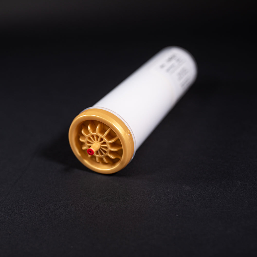 A small white tube with gold and red caps displayed on a black background, creating a striking visual contrast between the two elements.