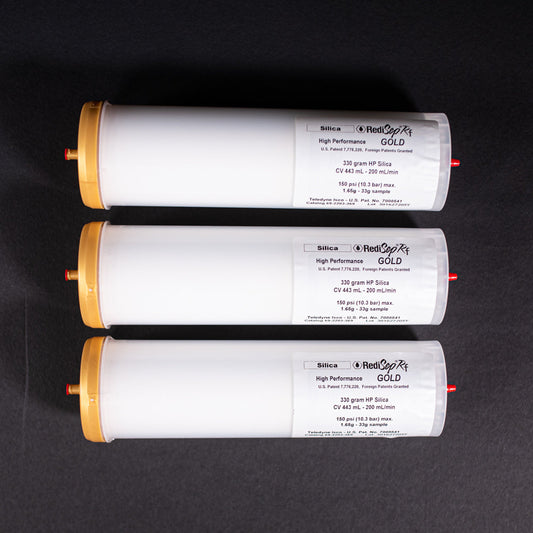 A group of small white tubes with gold and red caps displayed on a black background, creating a striking visual contrast between the two elements.