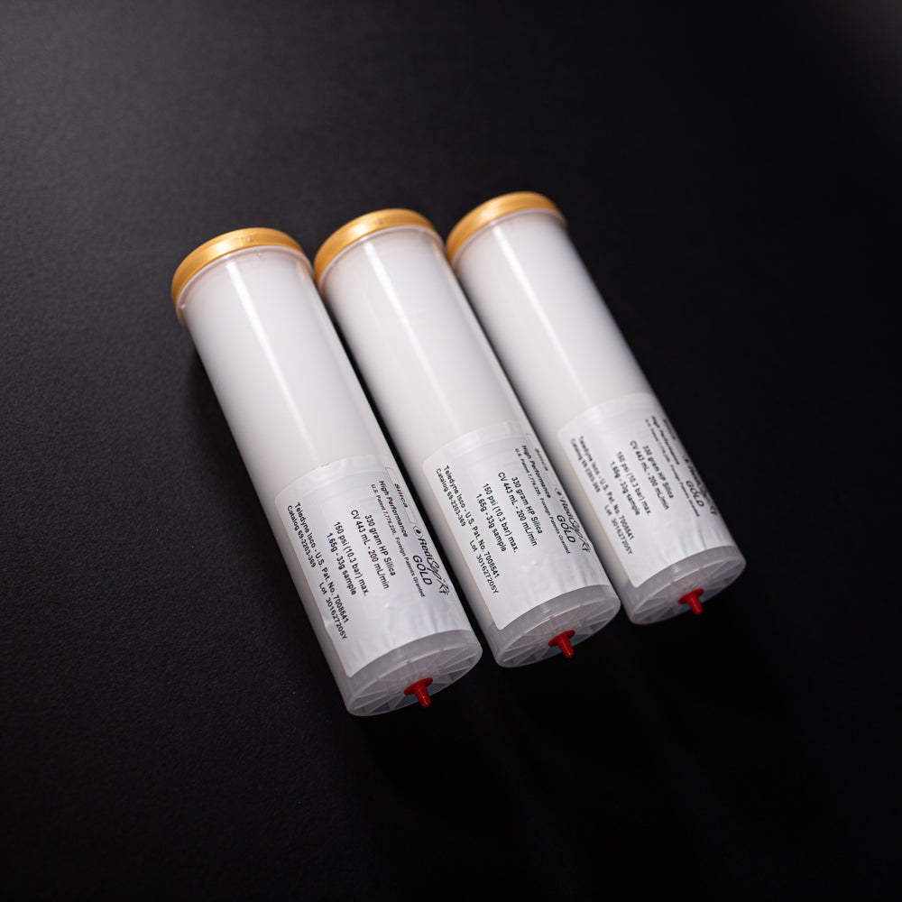 A group of small white tubes with gold and red caps displayed on a black background, creating a striking visual contrast between the two elements.