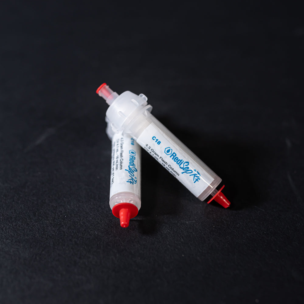 A pair of small white tubes with red caps displayed on a black background, creating a striking visual contrast between the two elements.