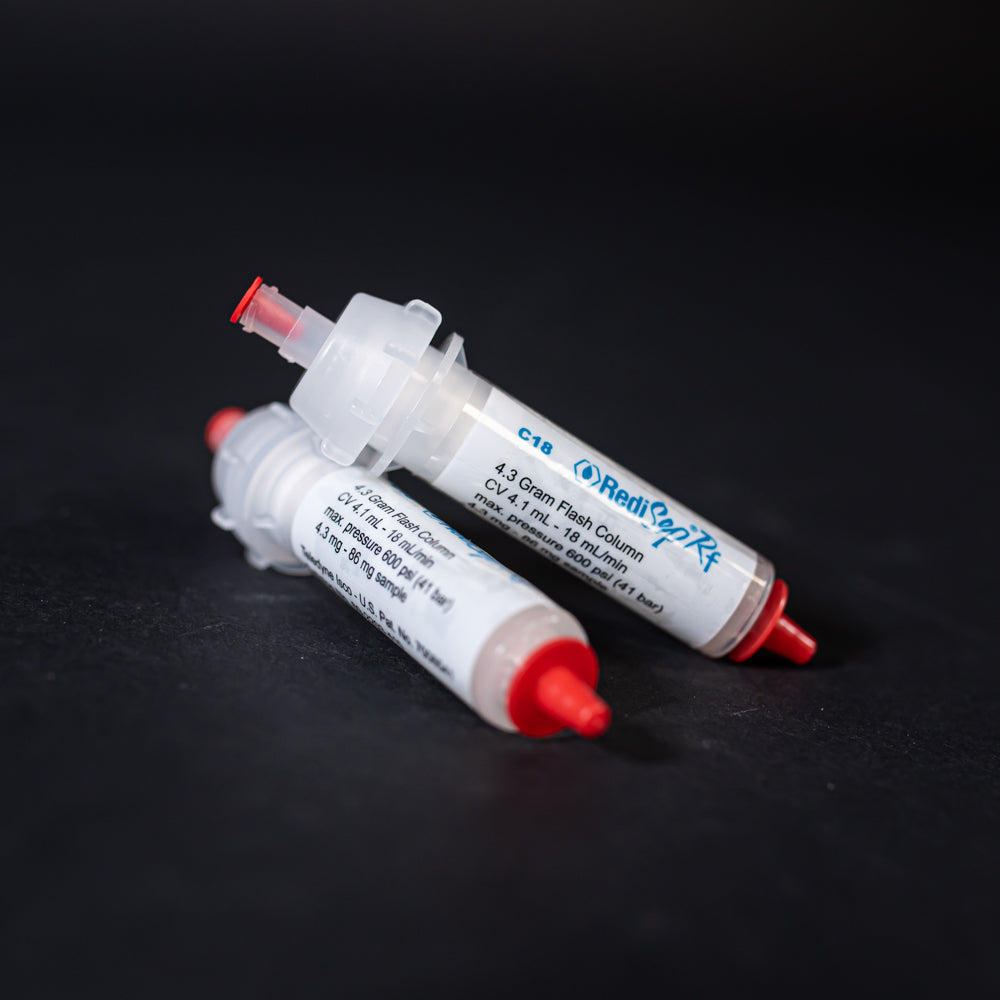 A pair of small white tubes with red caps displayed on a black background, creating a striking visual contrast between the two elements.