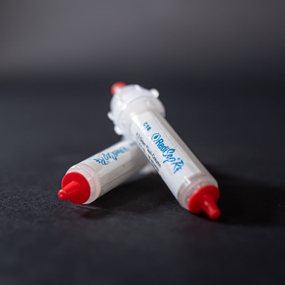 A pair of small white tubes with red caps displayed on a black background, creating a striking visual contrast between the two elements.