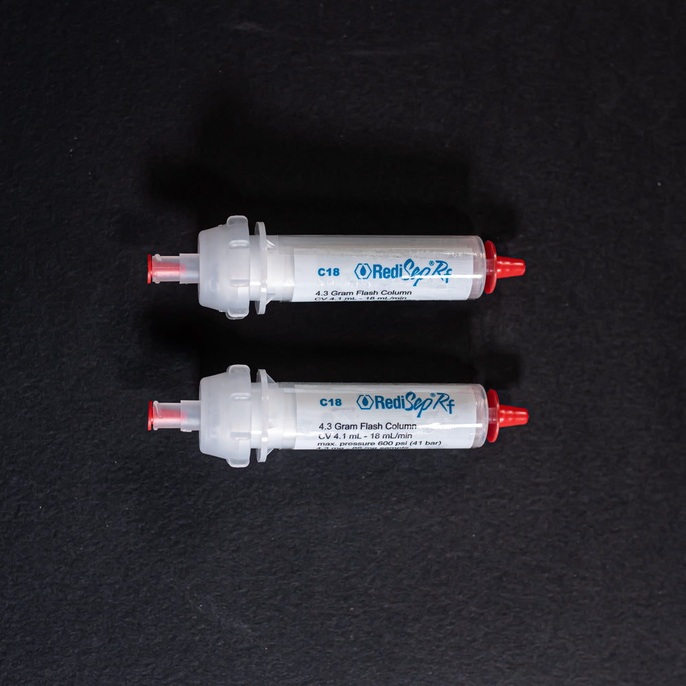 A pair of small white tubes with red caps displayed on a black background, creating a striking visual contrast between the two elements.