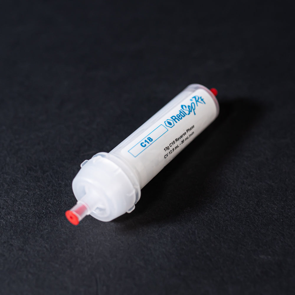 A small white tube with red caps displayed on a black background, creating a striking visual contrast between the two elements.
