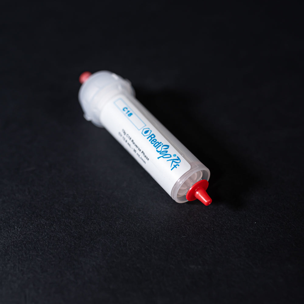 A small white tube with red caps displayed on a black background, creating a striking visual contrast between the two elements.