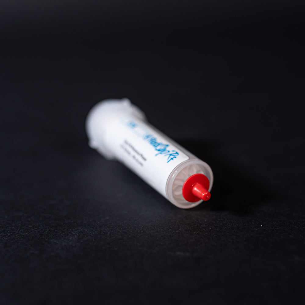 A small white tube with red caps displayed on a black background, creating a striking visual contrast between the two elements.