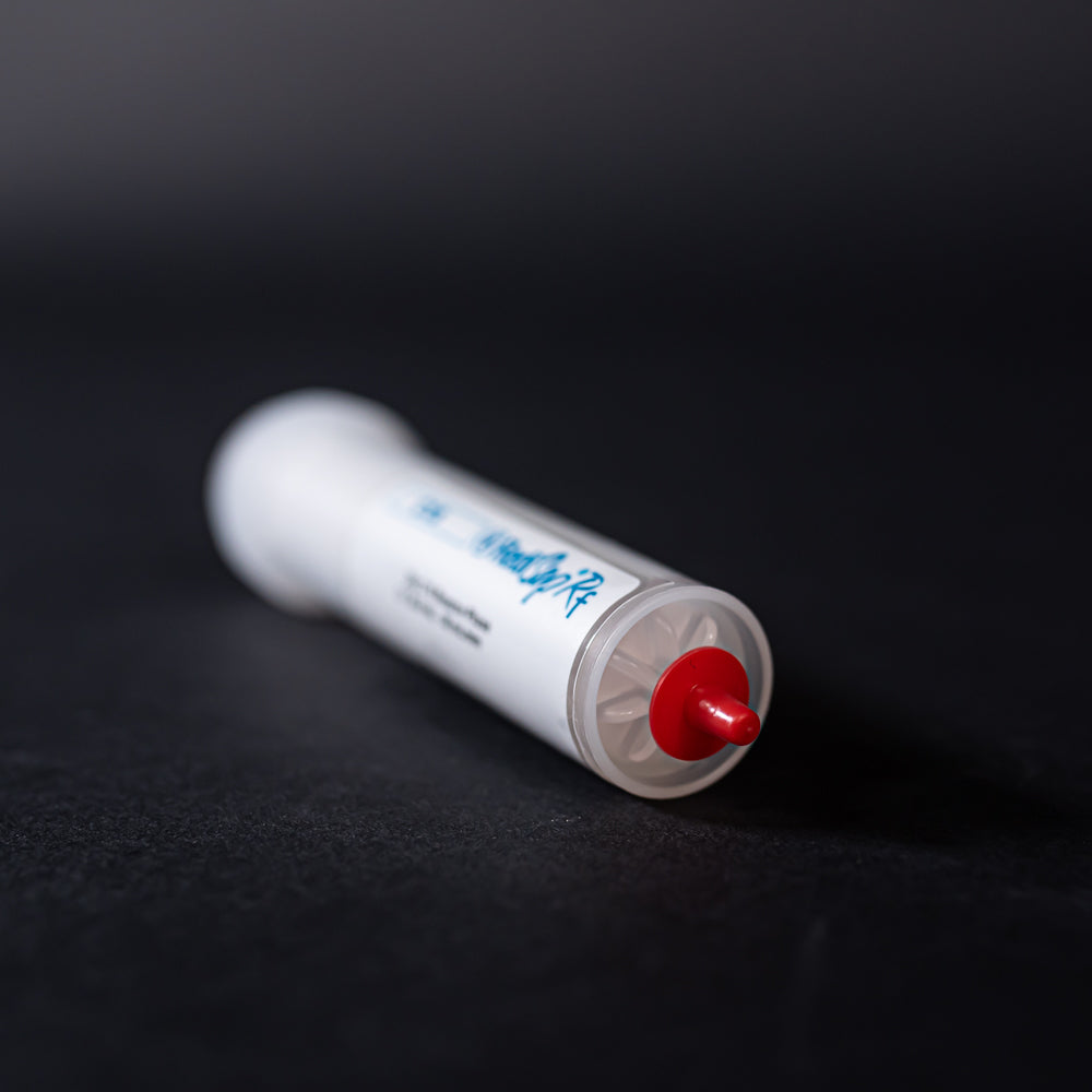 A small white tube with red caps displayed on a black background, creating a striking visual contrast between the two elements.