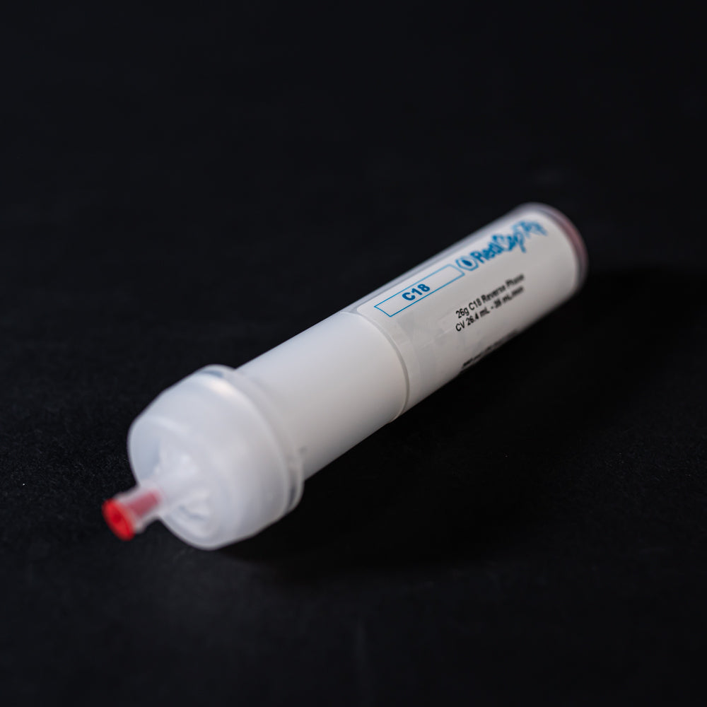 A small white tube with red caps displayed on a black background, creating a striking visual contrast between the two elements.