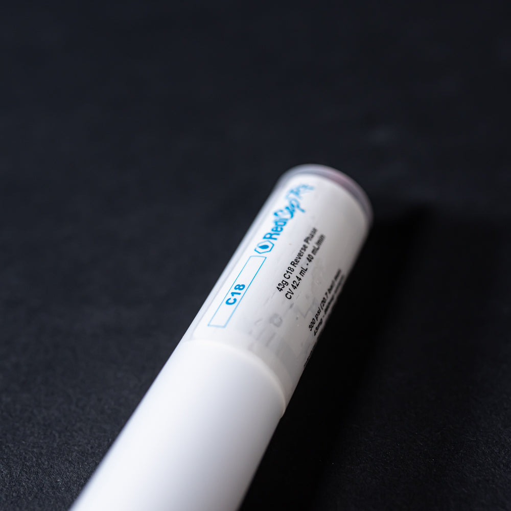 A small white tube with red caps displayed on a black background, creating a striking visual contrast between the two elements.