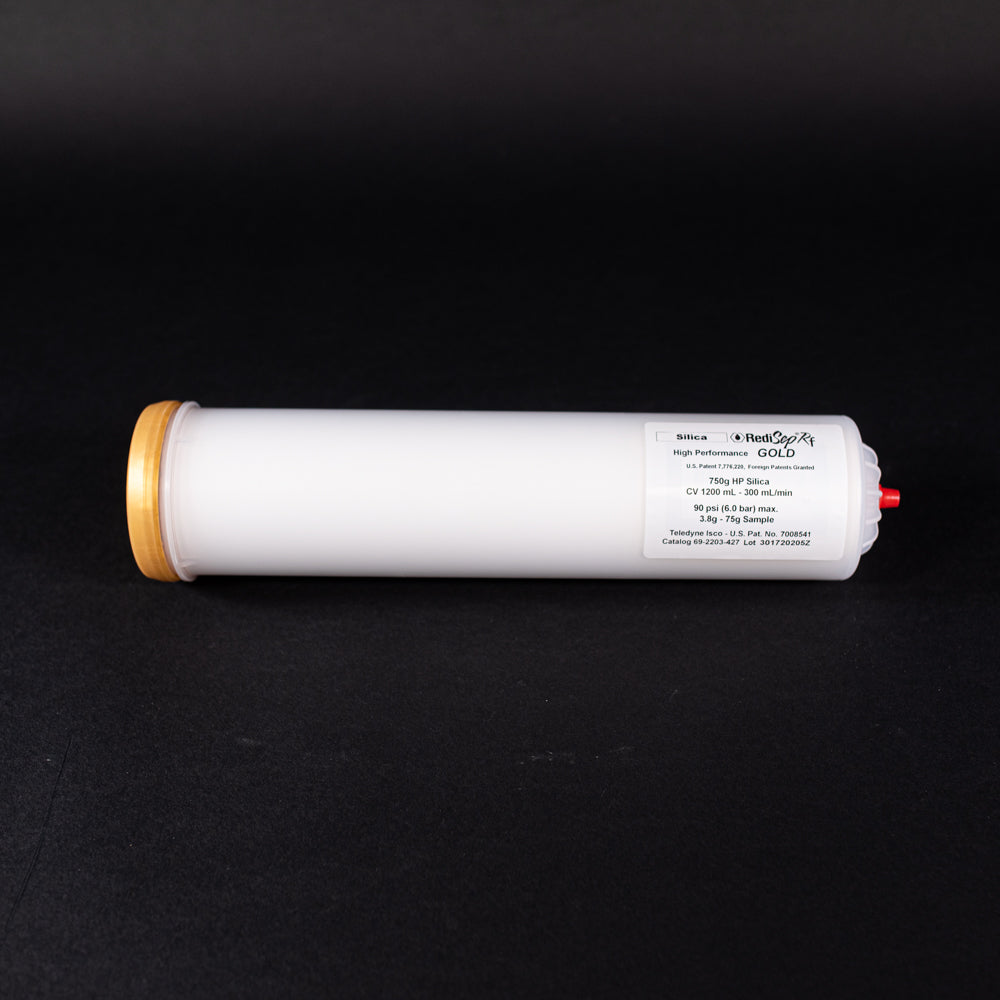 A small white tube with gold and red caps displayed on a black background, creating a striking visual contrast between the two elements.