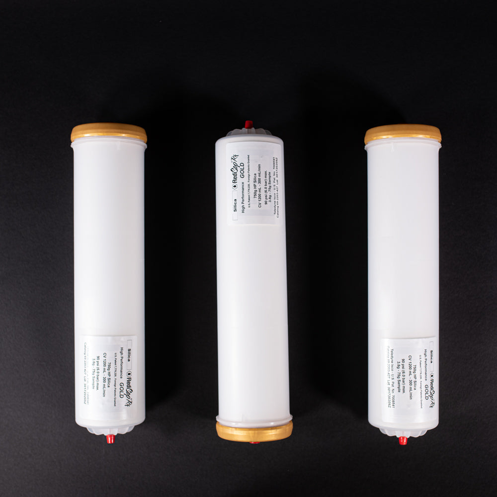 A group of small white tubes with gold and red caps displayed on a black background, creating a striking visual contrast between the two elements.