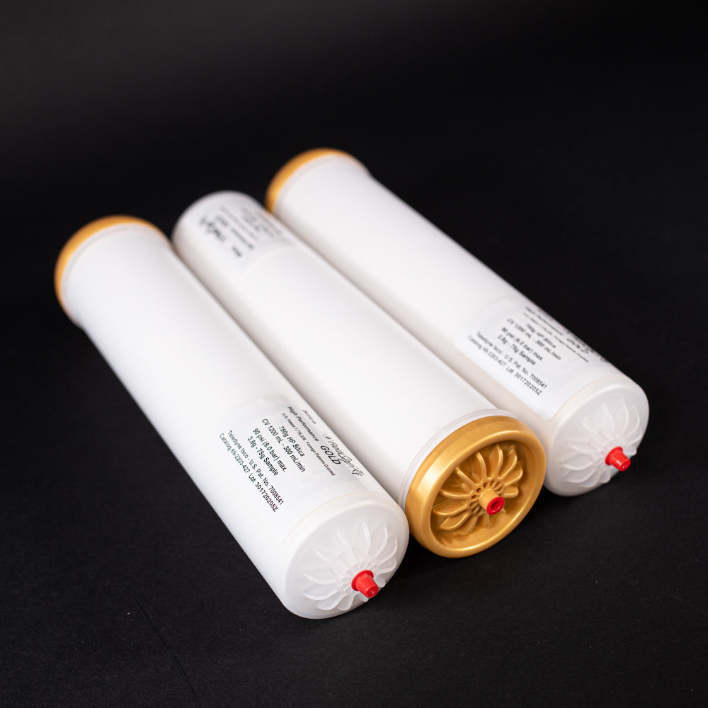 A group of small white tubes with gold and red caps displayed on a black background, creating a striking visual contrast between the two elements.