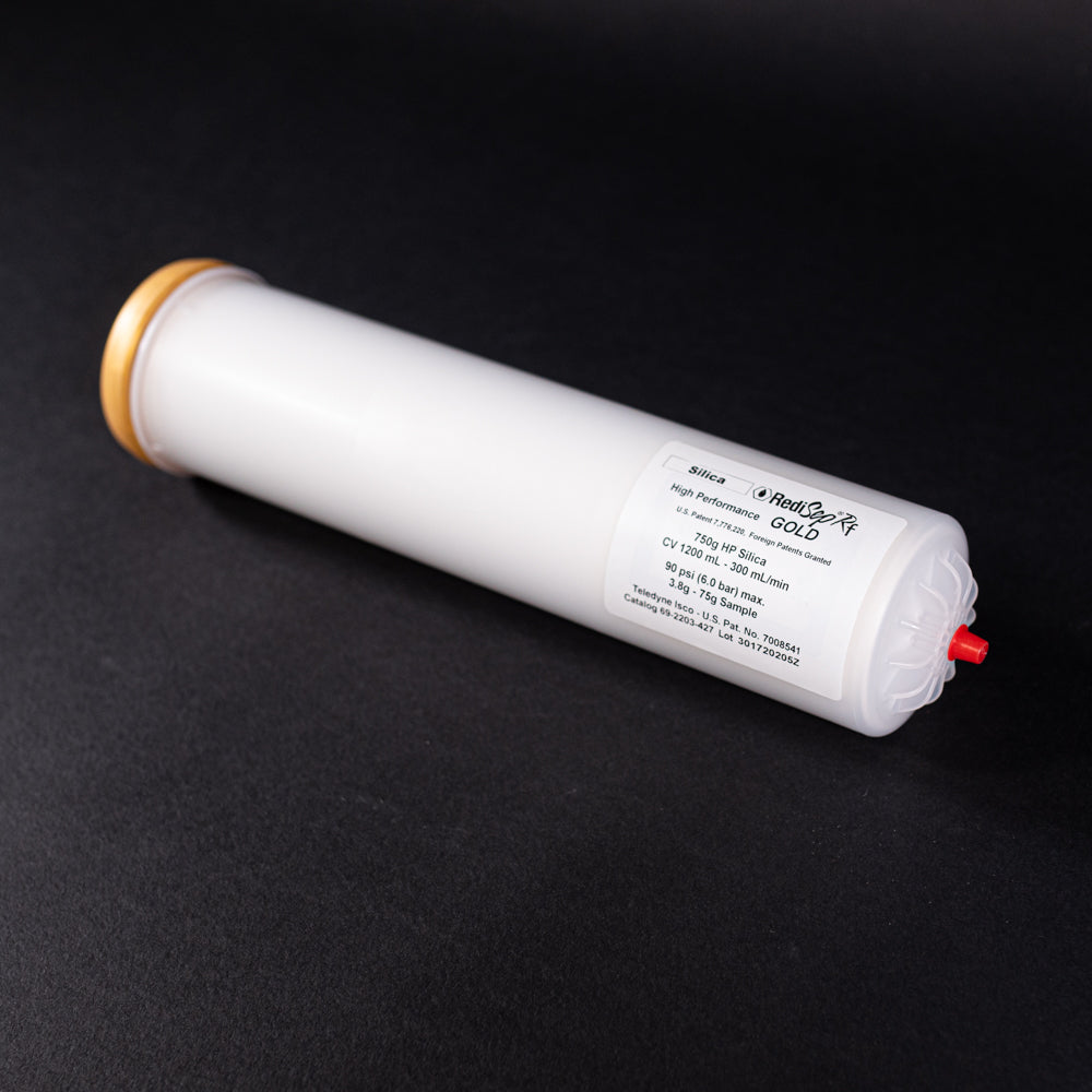 A small white tube with gold and red caps displayed on a black background, creating a striking visual contrast between the two elements.