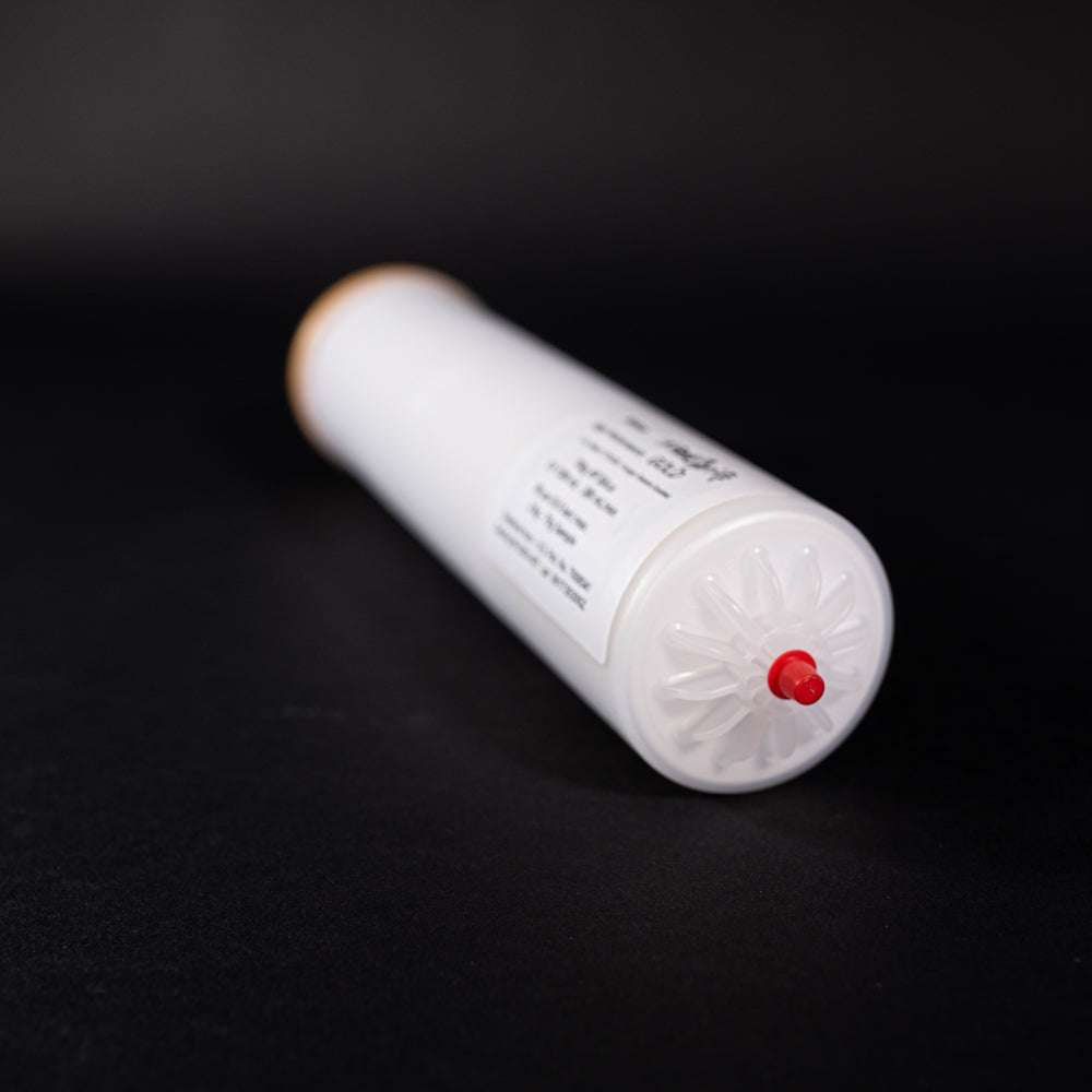 A small white tube with gold and red caps displayed on a black background, creating a striking visual contrast between the two elements.
