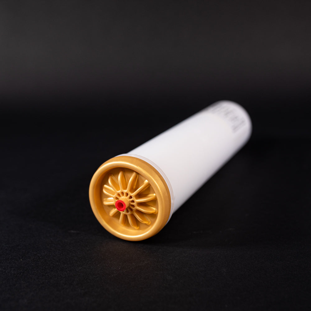 A small white tube with gold and red caps displayed on a black background, creating a striking visual contrast between the two elements.