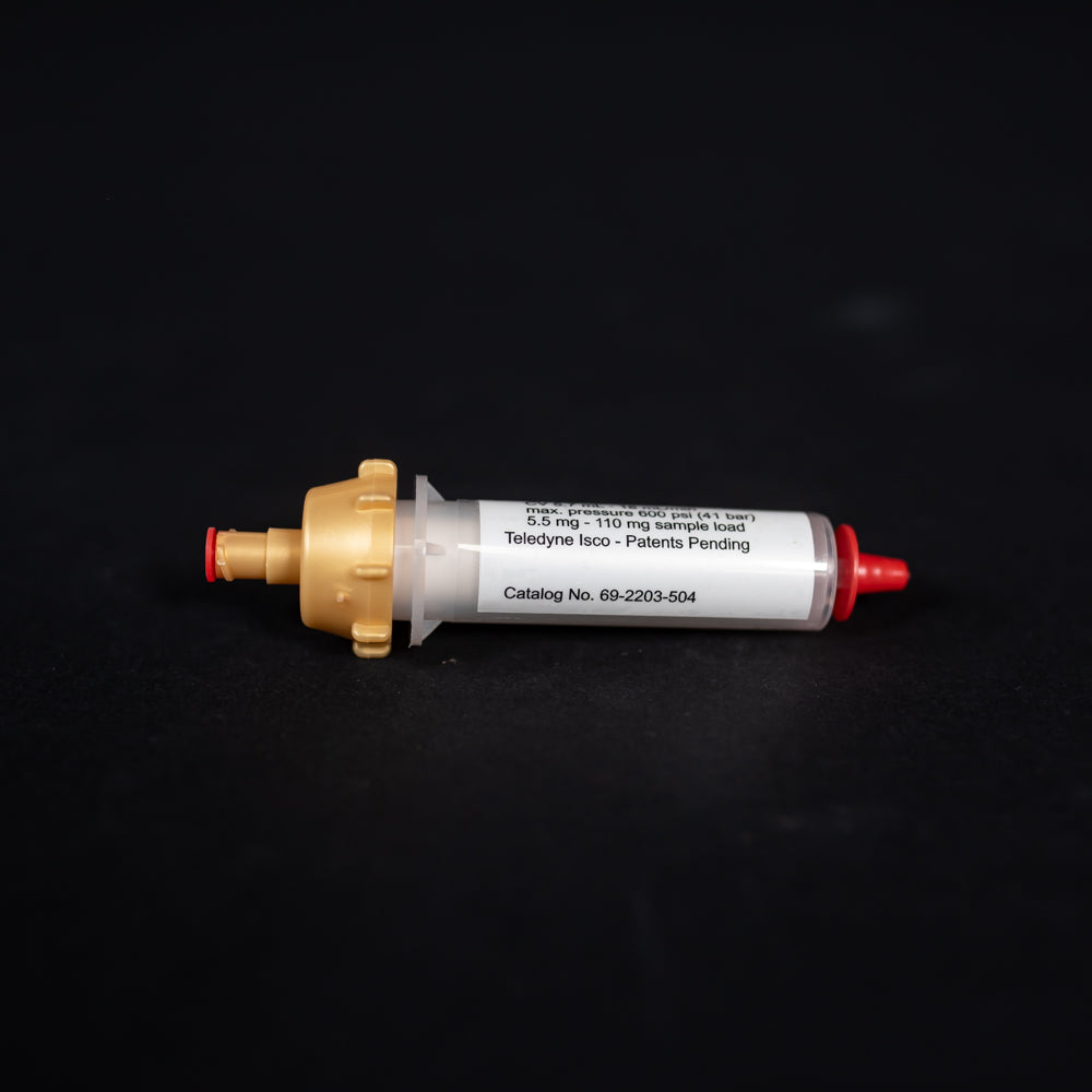 A small white tube with gold and red caps displayed on a black background, creating a striking visual contrast between the two elements.